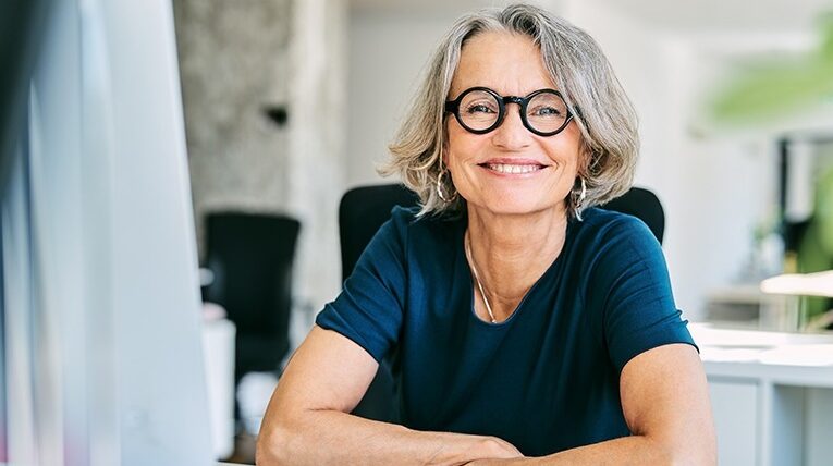 femme-souriante-assise-a-son-bureau