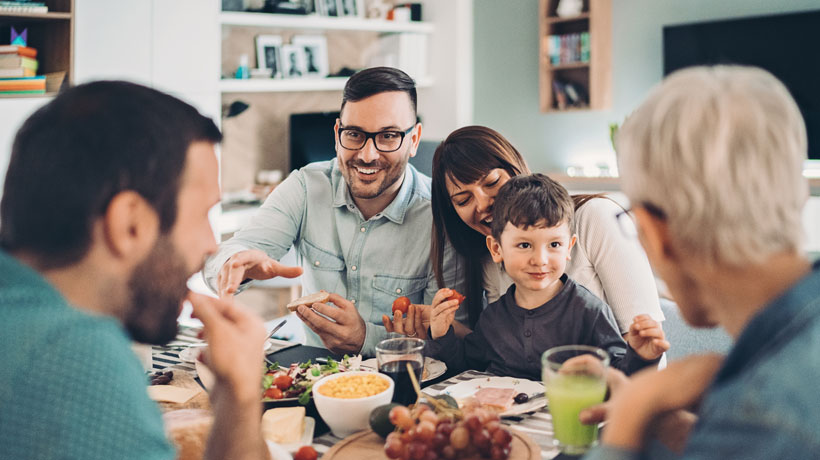 Une famille souriante à table qui illustrent nos offres d'assurance