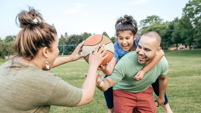 adultes et enfant jouant au ballon à l'extérieur