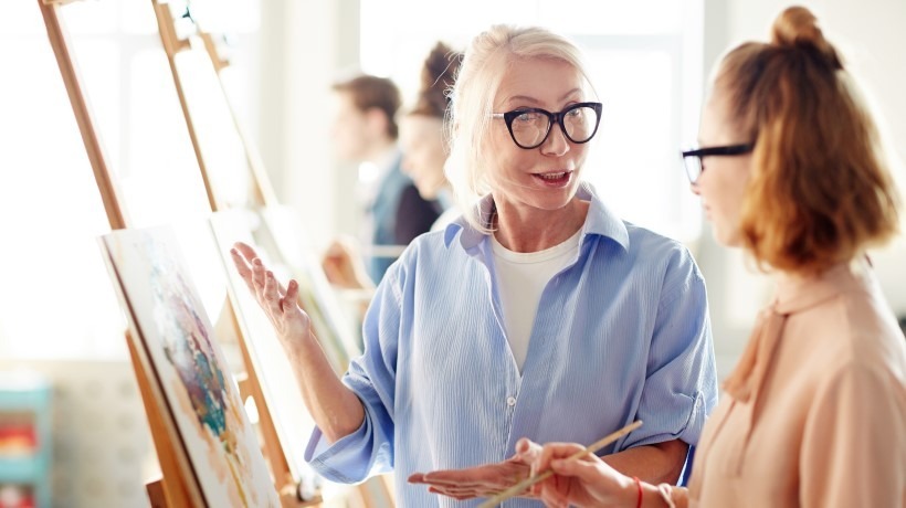 2 personnes qui regardent une toile de peinture avec une artiste